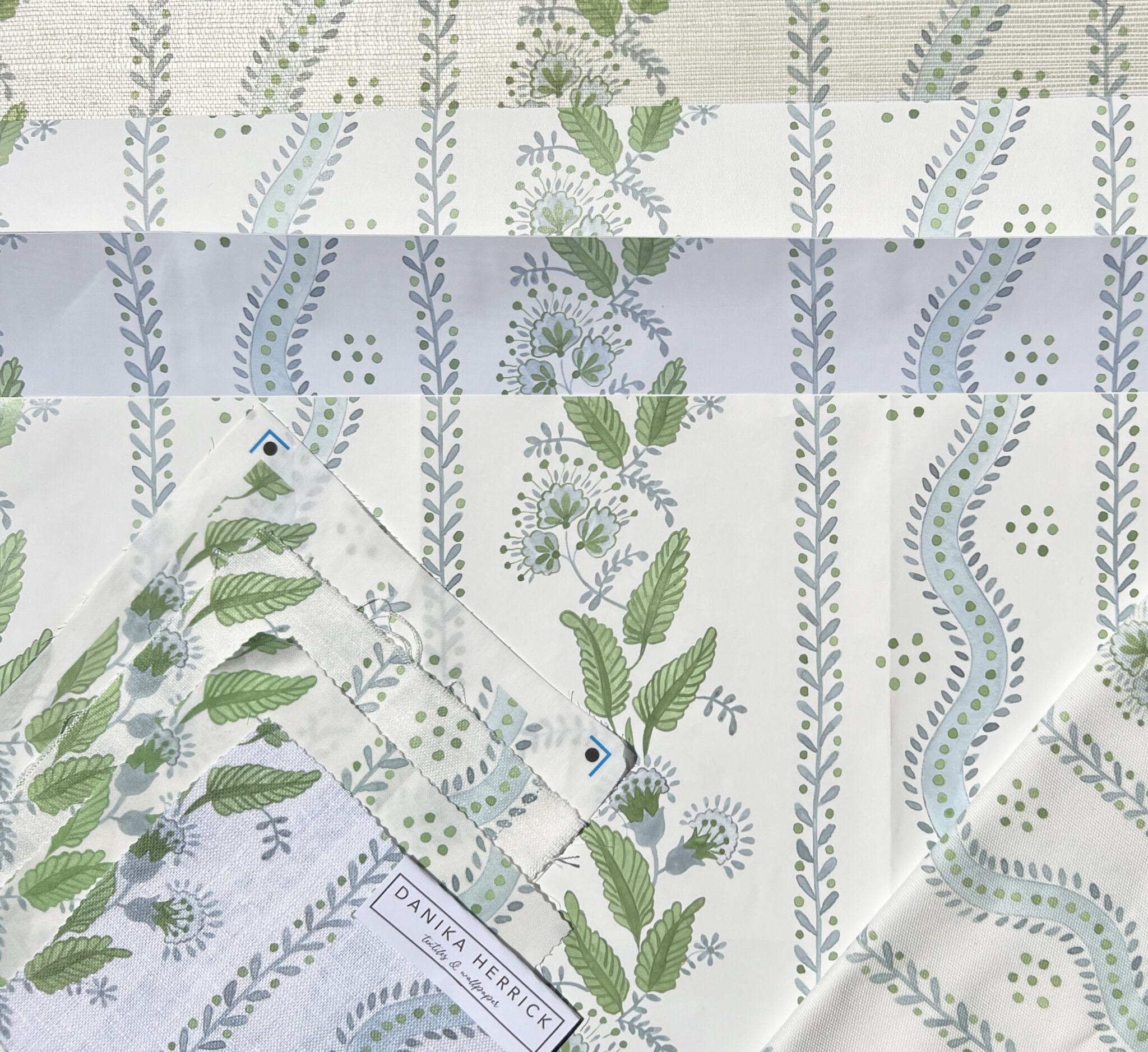a soft blue and green floral and striped design printed on different fabrics and wallpapers
