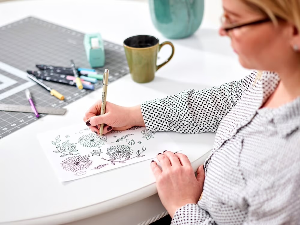 female artist hand drawing flowers on paper