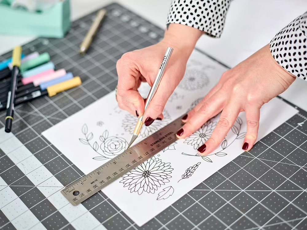 flower drawing being cut in half with a ruler and x-acto knife