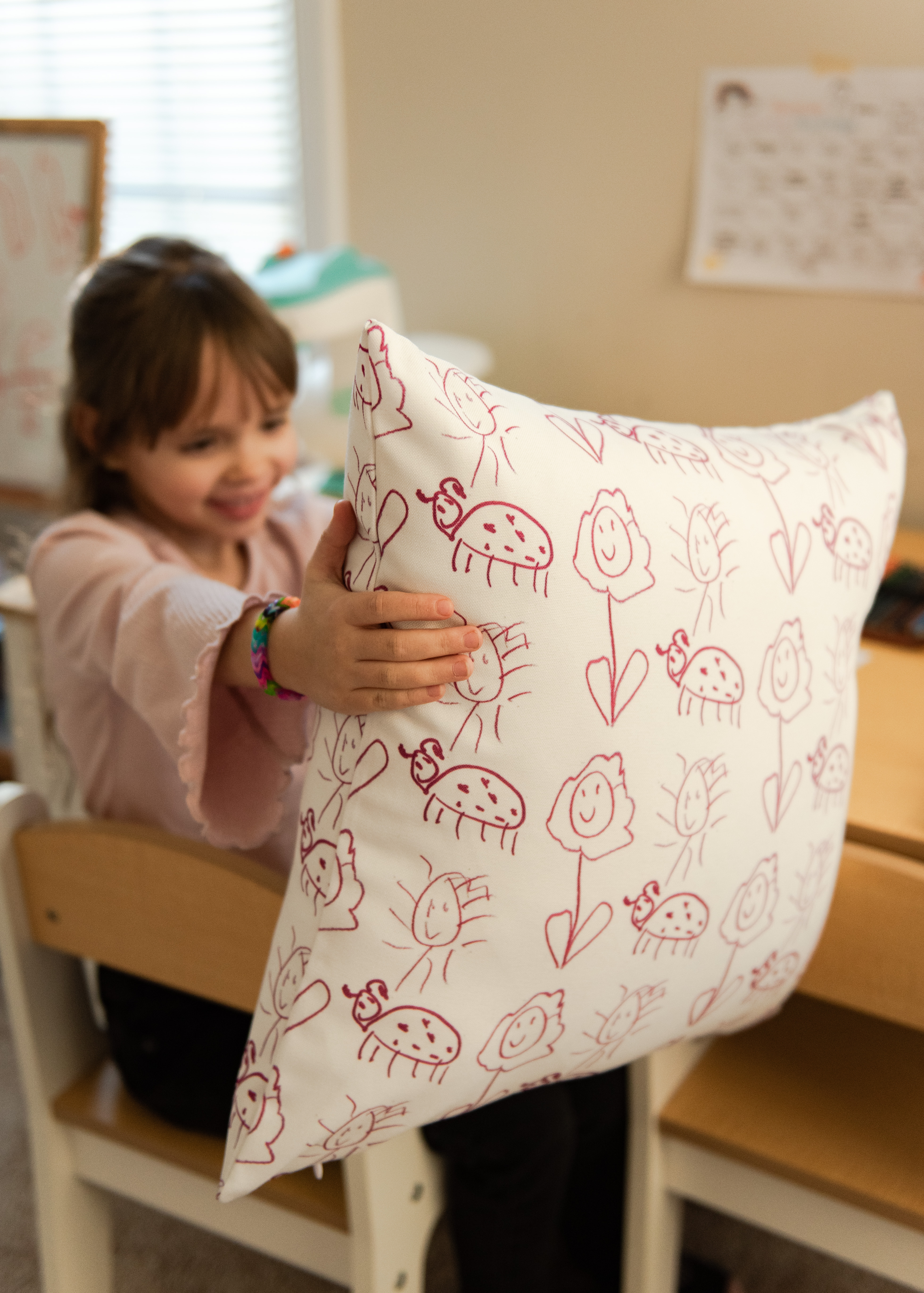 photo of girl holding pillow with her handdrawn designs